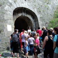 Uczestnicy treningu zwiedzają historyczy obiekt, w tle widać przewodnika, stare mury z wejściem prowadzącą do obiektu