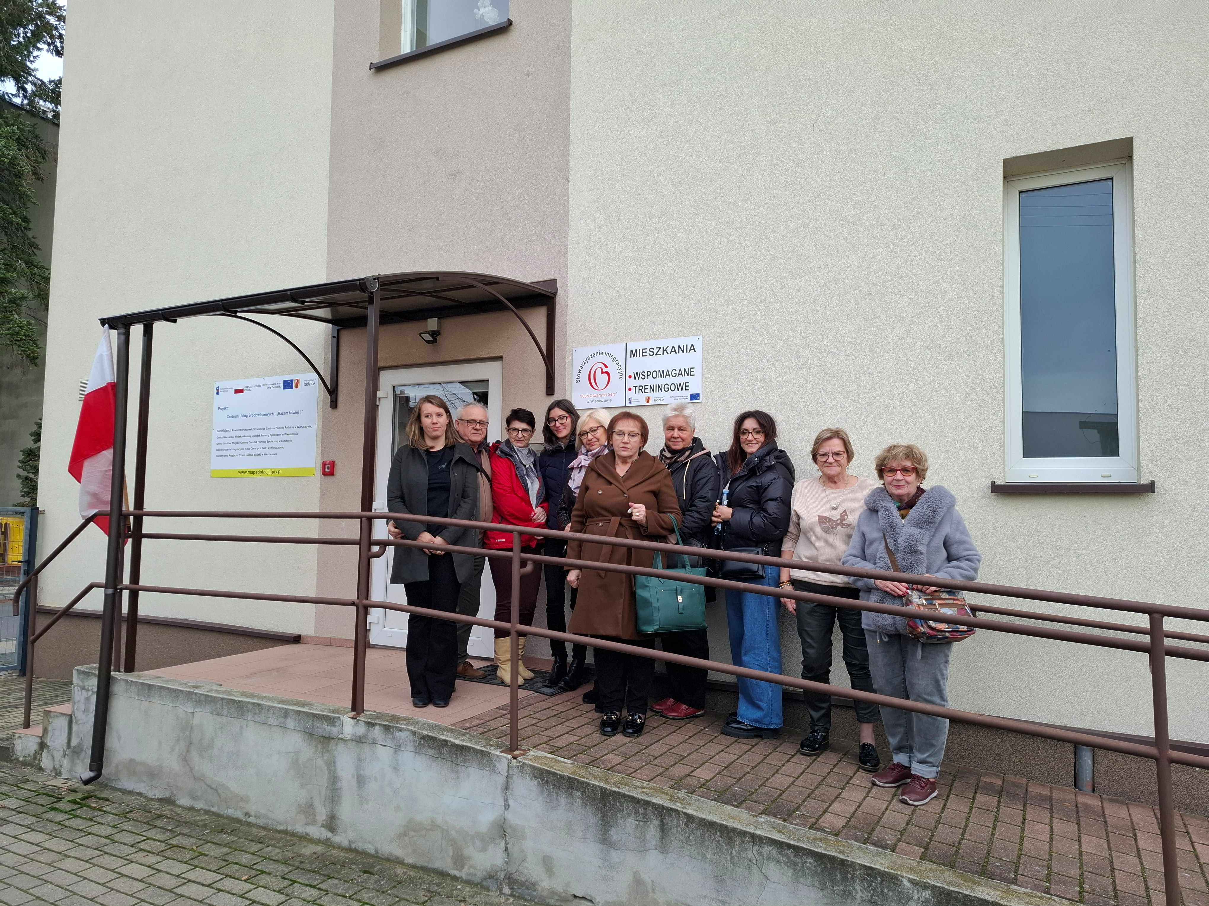 Zdjęcie grupowe uczestników wizyty studyjnej przed budynkiem mieszkań treningowych i wspieranych