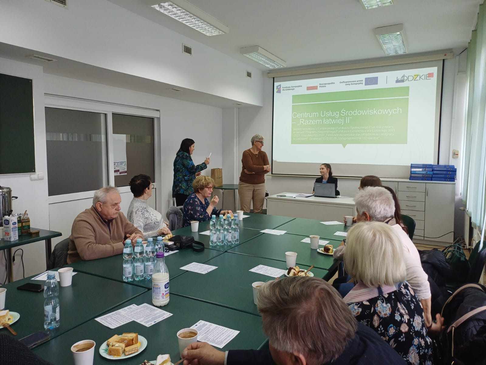 uczestnicy wizyty studyjnej przy stole, w tle prezentacja dot. projektu