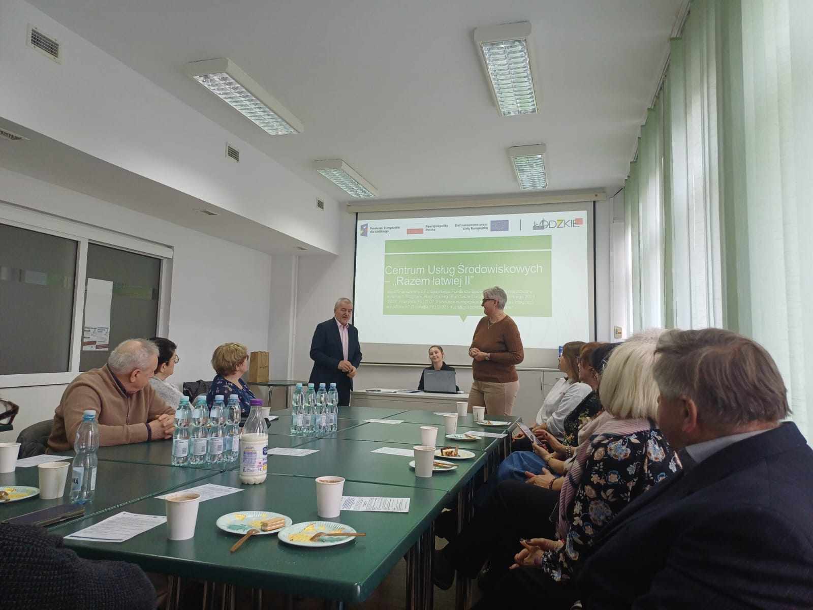 uczestnicy wizyty studyjnej przy stole, w tle prezentacja dot. projektu