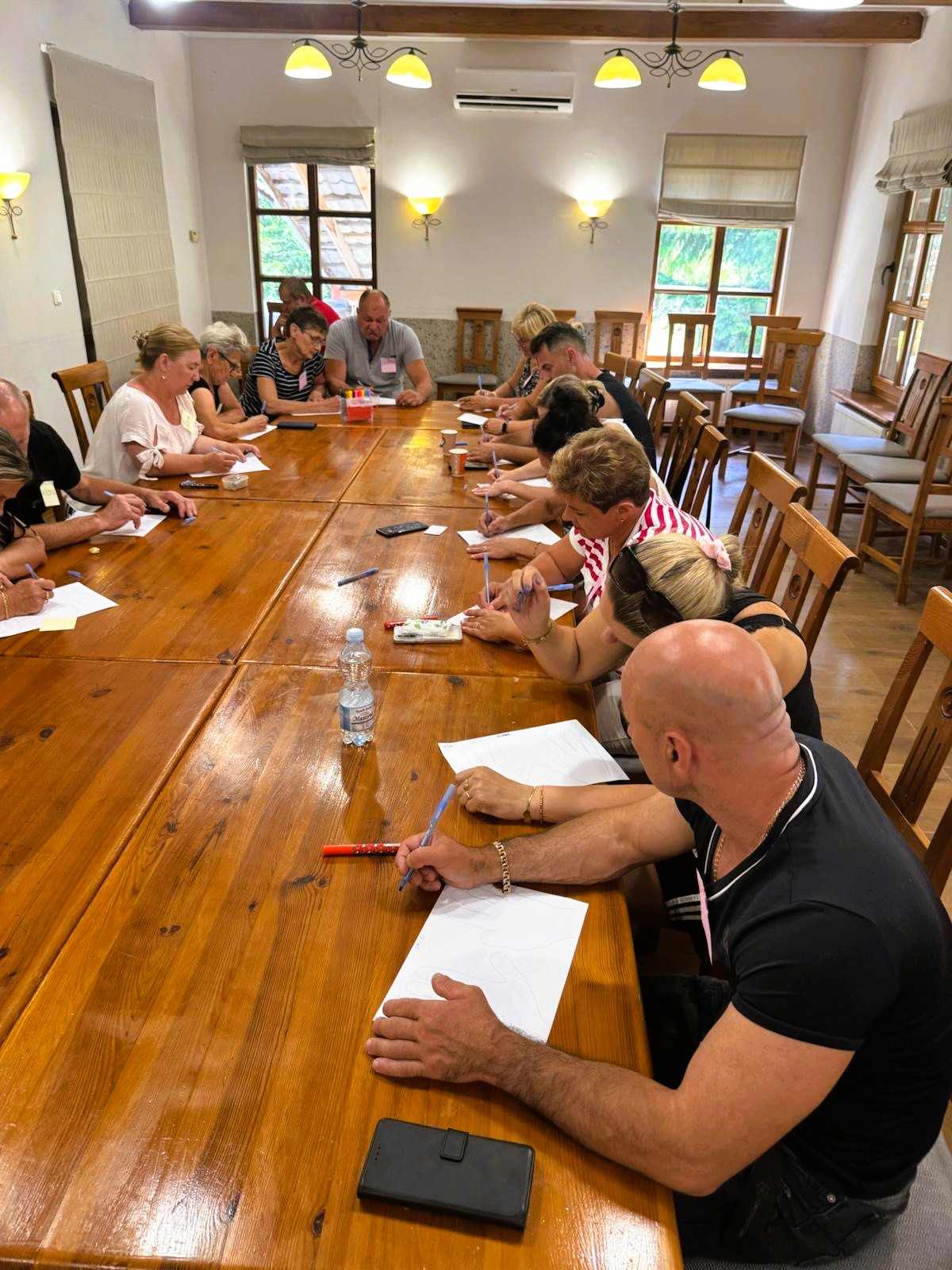 Grupa osób siedząca przy stole podczas zajęć Grupa osób siedząca przy stole podczas zajęć